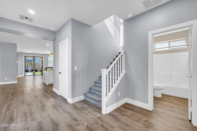 an empty room with wooden floor ceiling fan and windows