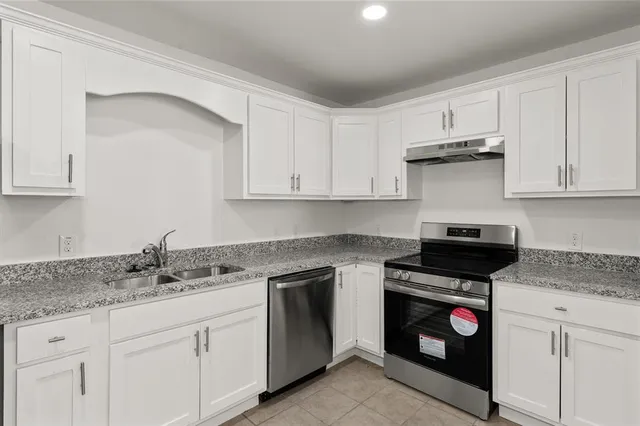 a kitchen with granite countertop white cabinets and stainless steel appliances
