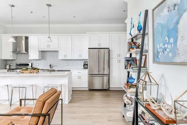 a kitchen with stainless steel appliances granite countertop a refrigerator a stove a sink dishwasher and white cabinets with wooden floor