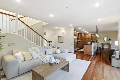 a living room with furniture kitchen view and a wooden floor