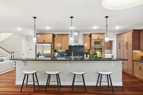 a kitchen with stainless steel appliances a dining table chairs and white cabinets