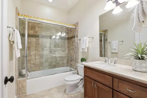a bathroom with a bathtub shower sink vanity mirror and toilet