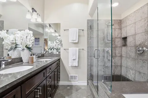 a bathroom with a granite countertop shower sink and mirror