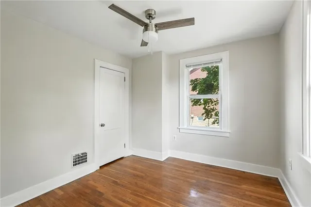 a view of an empty room with a window and wooden floor