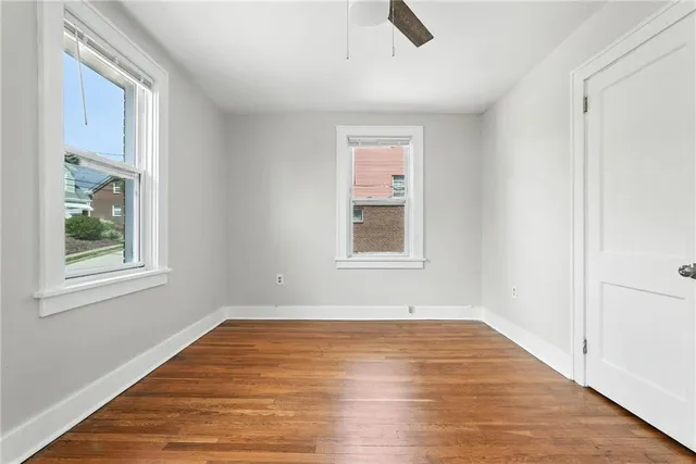 a view of an empty room with window and wooden floor
