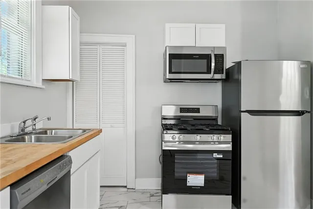 a kitchen with white cabinets and stainless steel appliances