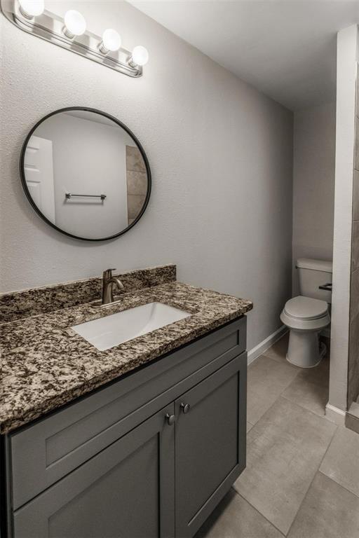 700 North Church Street Decatur, TX 76234 - Photo 14 of 15 a bathroom with a granite countertop toilet sink and mirror