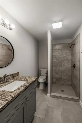 a bathroom with a granite countertop sink a toilet and a shower