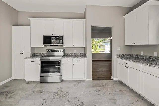 a kitchen with granite countertop white cabinets and stainless steel appliances