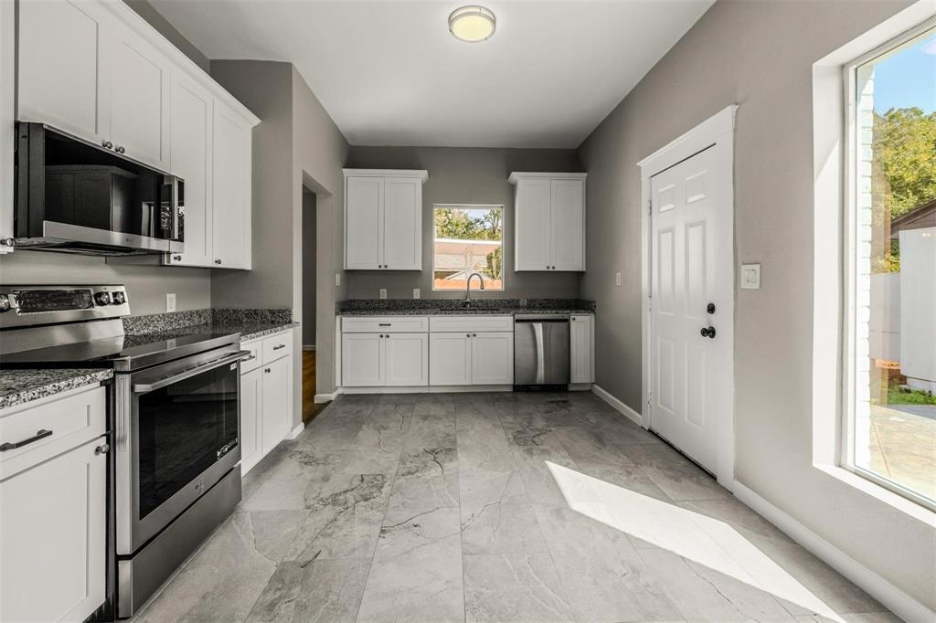 700 North Church Street Decatur, TX 76234 - Photo 8 of 15 a kitchen with stainless steel appliances granite countertop a stove a sink and a microwave
