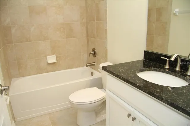 a bathroom with a granite countertop sink a toilet and bathtub