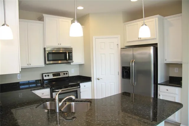 a kitchen with stainless steel appliances granite countertop a refrigerator a stove a sink and a microwave