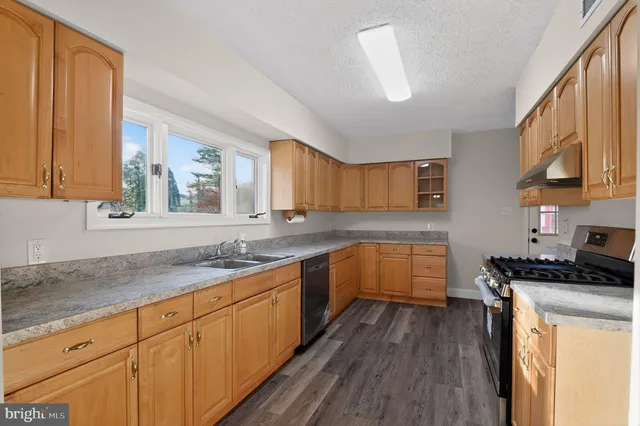a kitchen with granite countertop a sink a counter top space and cabinets