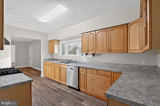 a kitchen with granite countertop a sink stove and cabinets