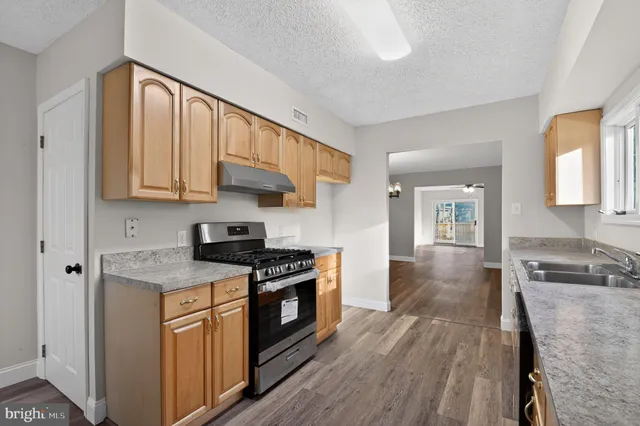 a kitchen with stainless steel appliances granite countertop wooden cabinets stove top oven and sink