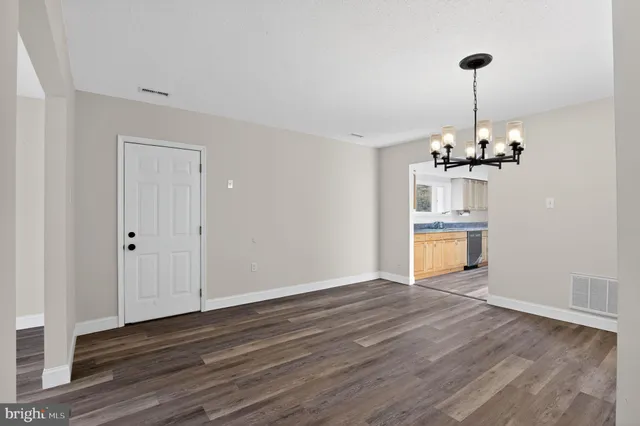 a view of a room with wooden floor chandelier and a window