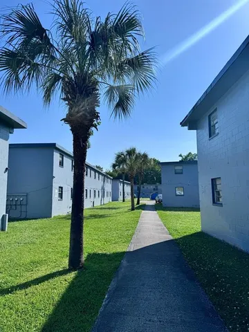 a swimming pool with a yard and palm trees