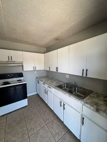 a large kitchen with granite countertop a stove and a sink