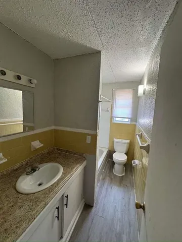 a bathroom with a granite countertop sink a mirror and a toilet