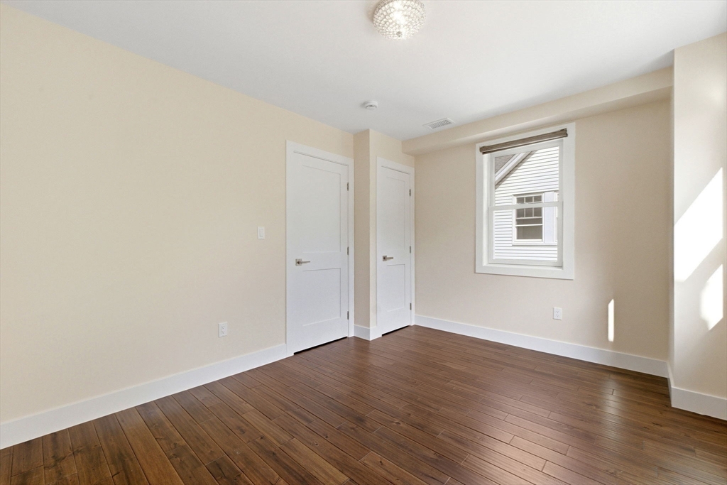 123 Nottinghill Road, Unit 2 Boston, MA 02135 - Photo 18 of 30 an empty room with wooden floor and windows