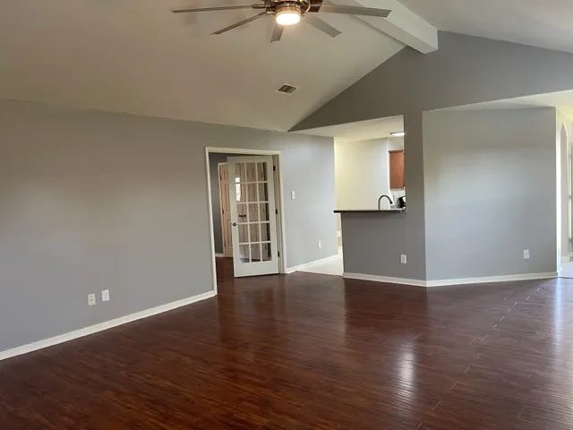 a view of an empty room with wooden floor and a ceiling fan