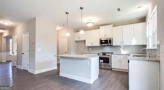 a open kitchen with white cabinets stainless steel appliances and wooden floor