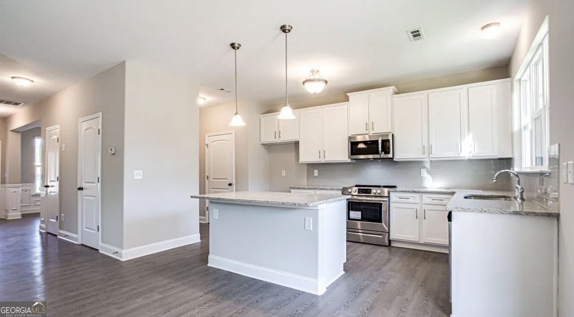 244 Sophie Circle Locust Grove, GA 30248 - Photo 4 of 11 a open kitchen with white cabinets stainless steel appliances and wooden floor