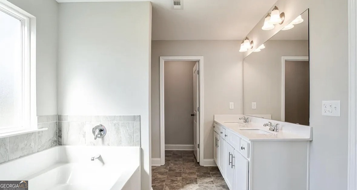 244 Sophie Circle Locust Grove, GA 30248 - Photo 7 of 11 a bathroom with a double vanity sink a mirror and a bathtub