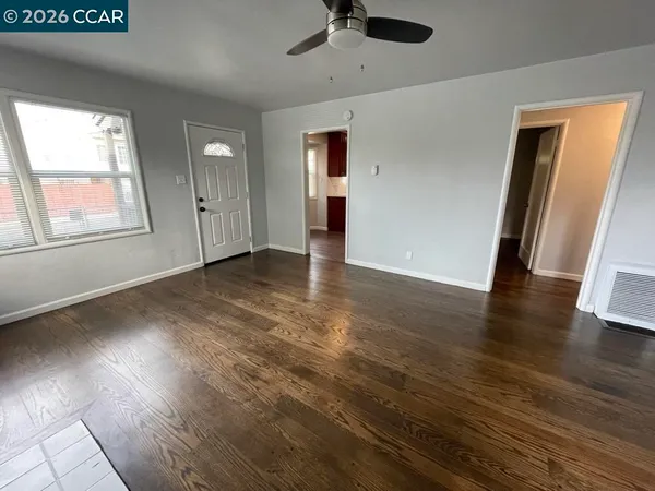 an empty room with wooden floor and windows