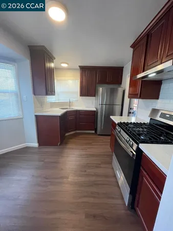 a large kitchen with wooden floors and stainless steel appliances