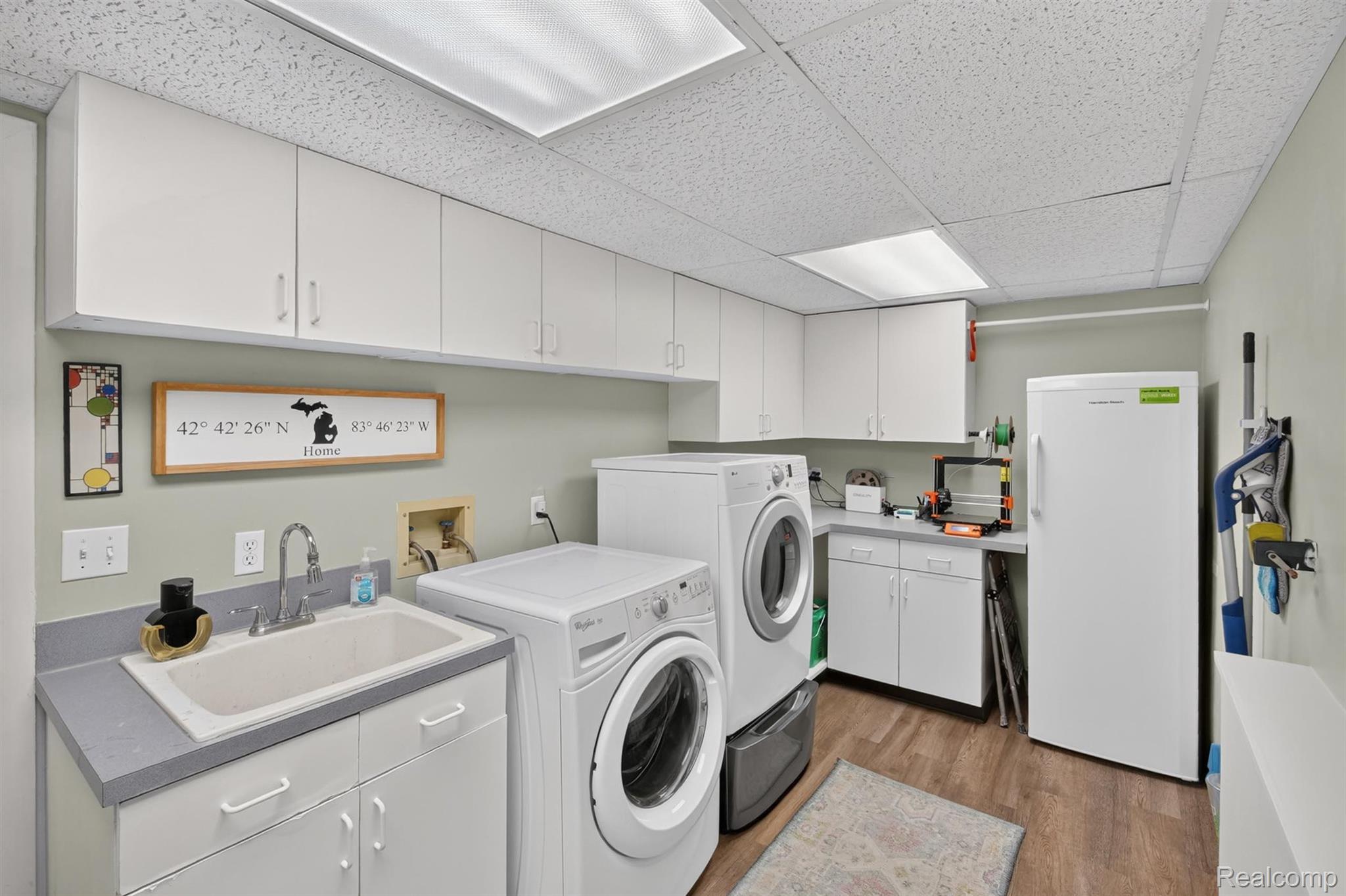 9319 Faussett Road Fenton, MI 48430 - Photo 25 of 70 White cabinetry with ample storage, utility sink, wood-finish flooring, and recessed ceiling lighting