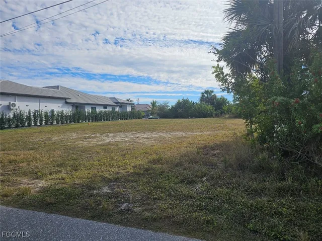 a view of a field with an ocean and trees