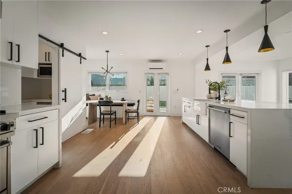 a kitchen with stainless steel appliances kitchen island granite countertop a stove a sink a refrigerator and white cabinets with wooden floor