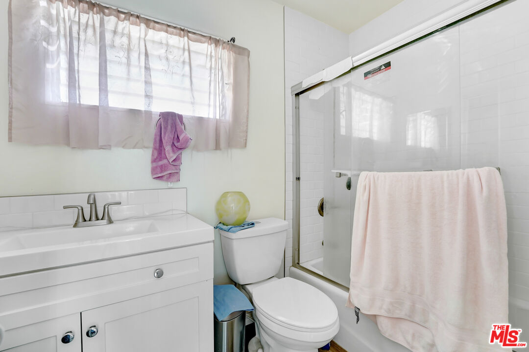 1740 Hauser Boulevard, Unit 8 Los Angeles, CA 90019 - Photo 6 of 10 a bathroom with a granite countertop sink toilet a mirror and shower