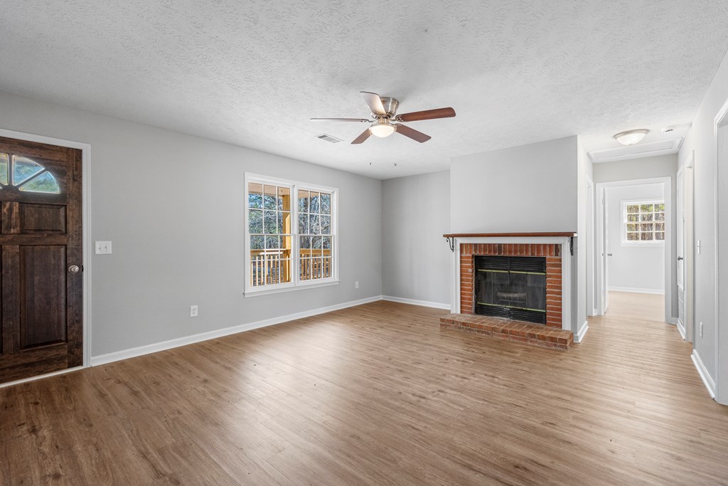 19110 Ga Highway Shiloh, GA 31826 - Photo 2 of 15 an empty room with wooden floor fireplace and windows