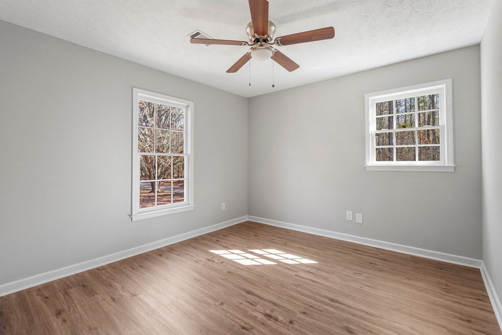 19110 Ga Highway Shiloh, GA 31826 - Photo 10 of 15 an empty room with wooden floor chandelier fan and windows