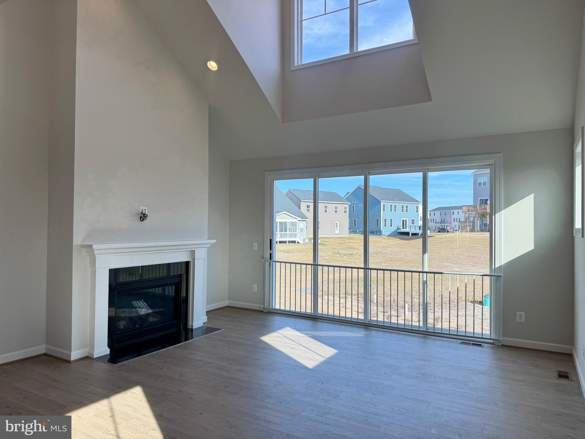 115 Sapphire Street Stephenson, VA 22656 - Photo 14 of 36 an empty room with wooden floor fireplace and windows