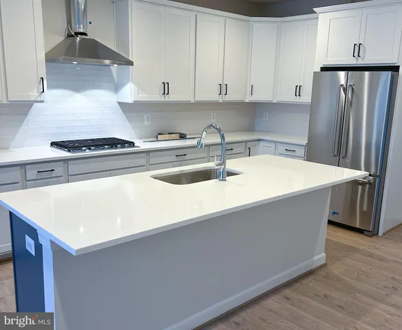a kitchen with stainless steel appliances a stove a refrigerator a sink and white cabinets