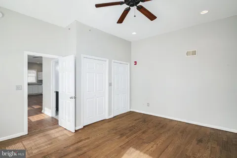a view of an empty room with wooden floor and window