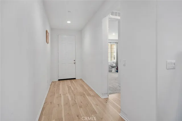 a view of a hallway with wooden floor and a bathroom