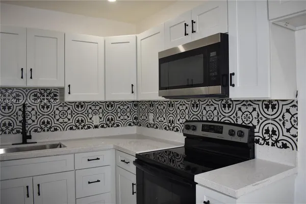 a kitchen with white cabinets and stainless steel appliances