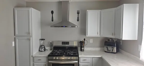 a kitchen with stainless steel appliances granite countertop white cabinets and a stove top oven