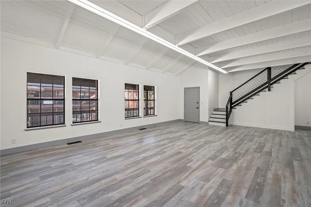 a view of an empty room with wooden floor and window