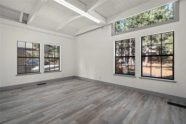 an empty room with wooden floor and windows