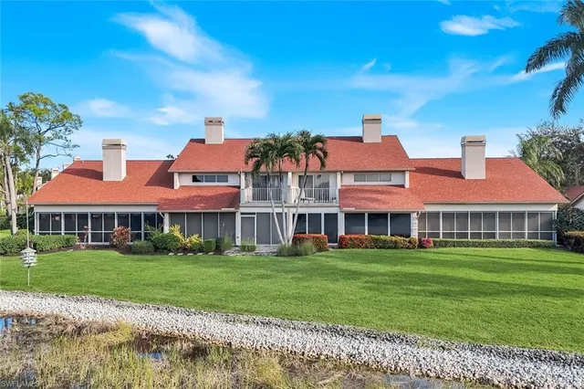 a front view of a building with garden and trees