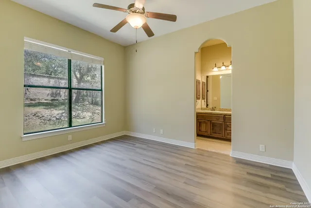 a view of empty room with wooden floor and fan
