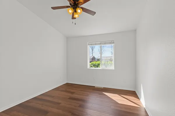 an empty room with a window and a ceiling fan