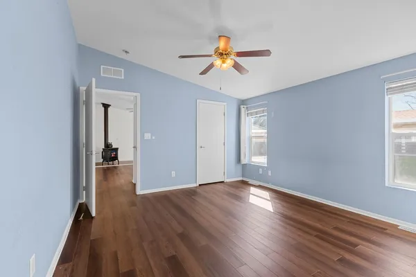 a view of an empty room with wooden floor and a window