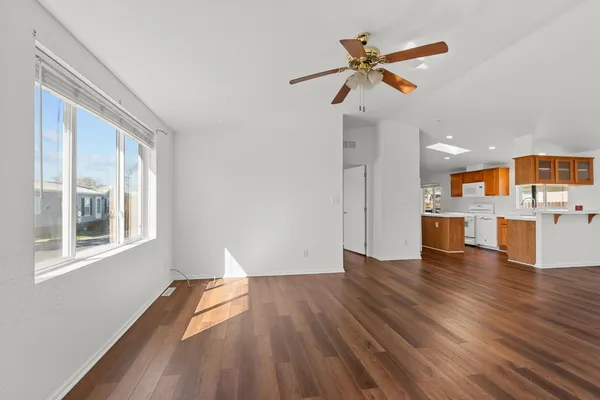 a view of an empty room with a window and wooden floor