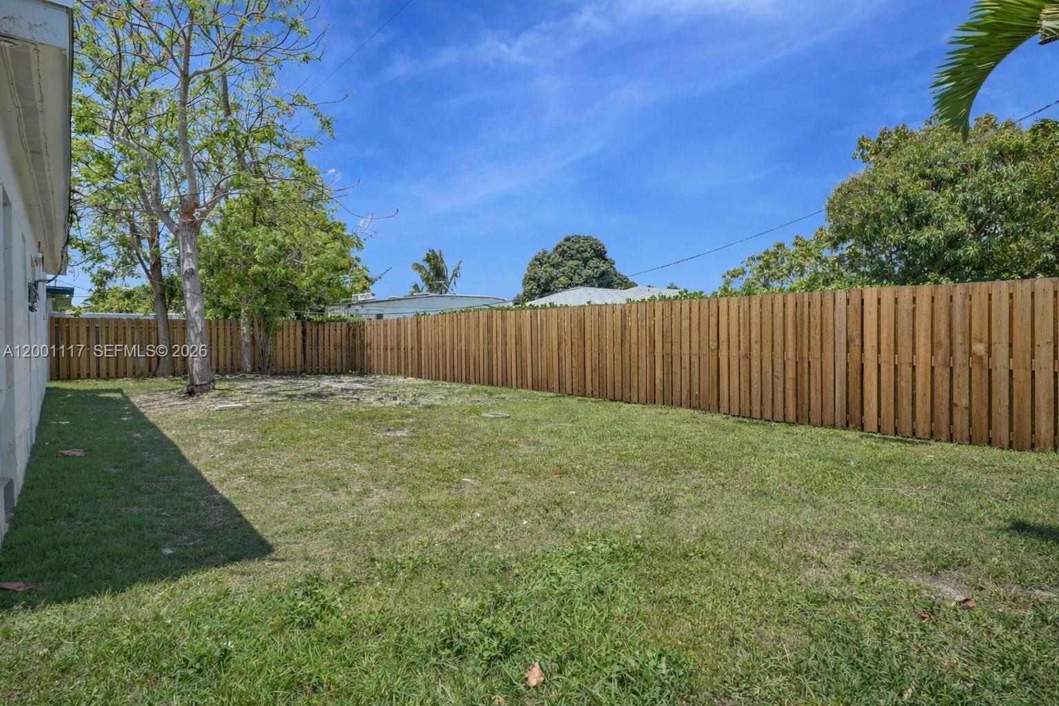 11775 Southwest 223rd Street Miami, FL 33170 - Photo 14 of 42 a view of a backyard with large tree and wooden fence